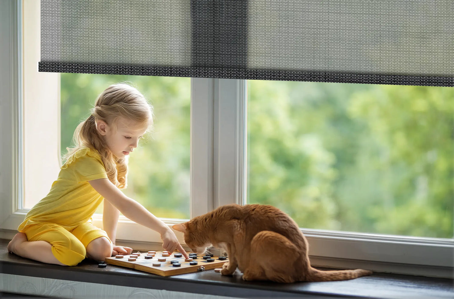 Child playing safely near a window with Kurlax cordless solar roller shades, eliminating cord entanglement risks.