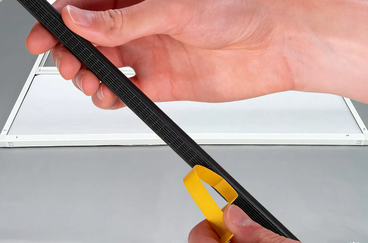 Peeling the backing off the adhesive sealing strip for no-drill installation.