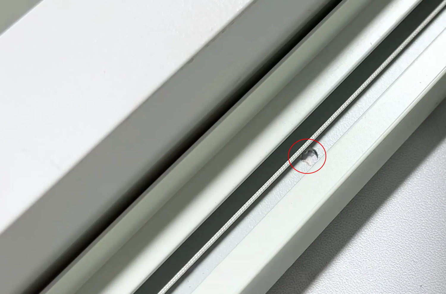 Using a power drill to drive screws through the side rail pilot holes and securing the bottom rail (over 80cm) to the window frame.